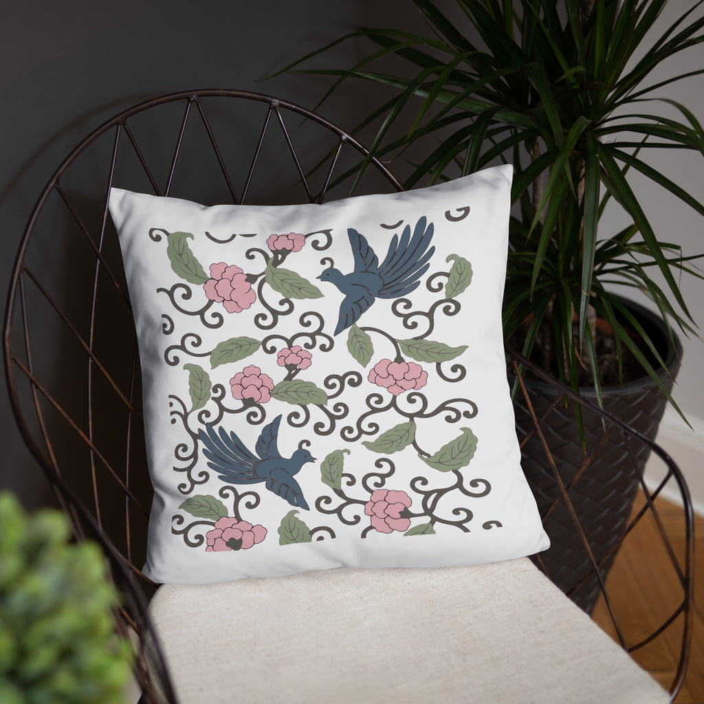 Weißes Dekokissen mit floralem Japandi-Motiv und Vogelillustrationen auf Stuhl