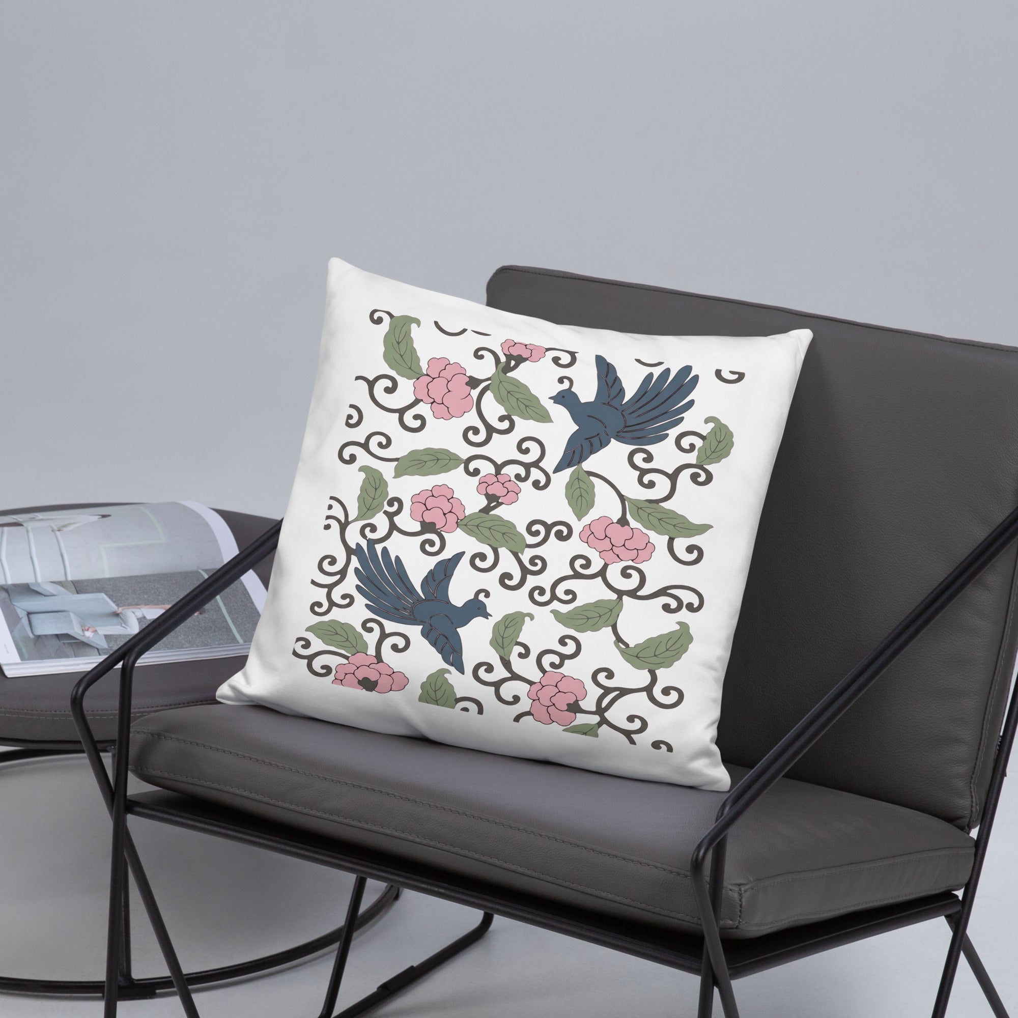 Weißes Dekokissen mit floralem Japandi-Motiv und Vogelillustrationen auf dunkler Stoffdecke im modernen Interior-Setting