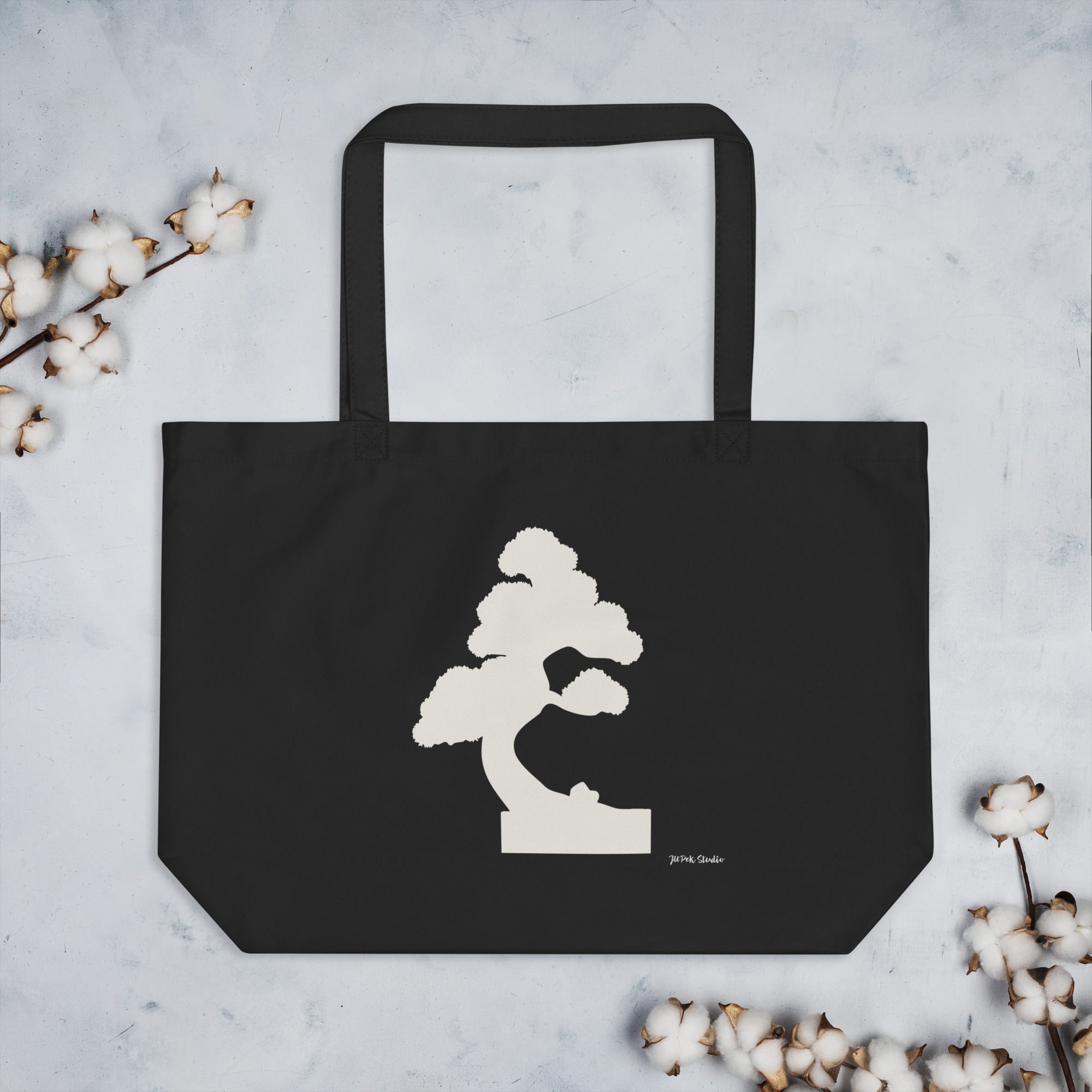 Große schwarze Baumwoll-Tote-Bag mit Off-White Bonsai-Illustration „Silent Pine“ von JUPek Studio, Frontansicht auf hellem Hintergrund