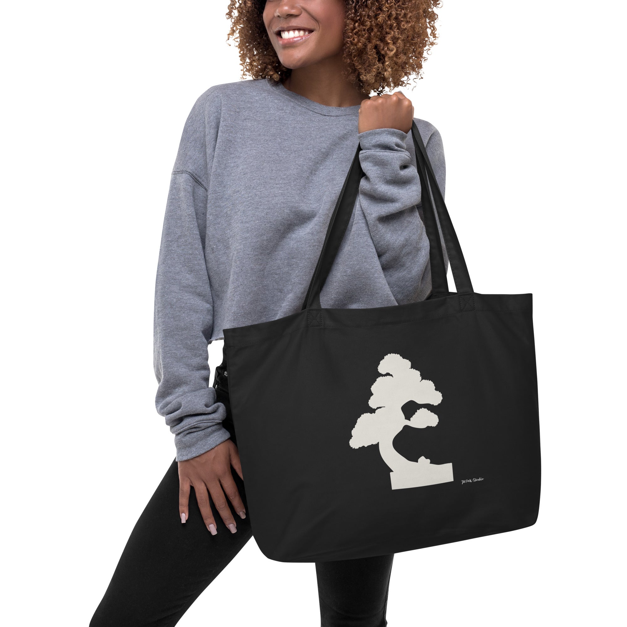 Person trägt große schwarze Tote-Bag mit Off-White Bonsai-Illustration „Silent Pine“ über der Schulter